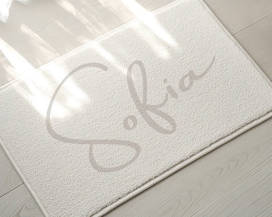 White doormat with 'Sofia' printed on it on a light wooden floor.