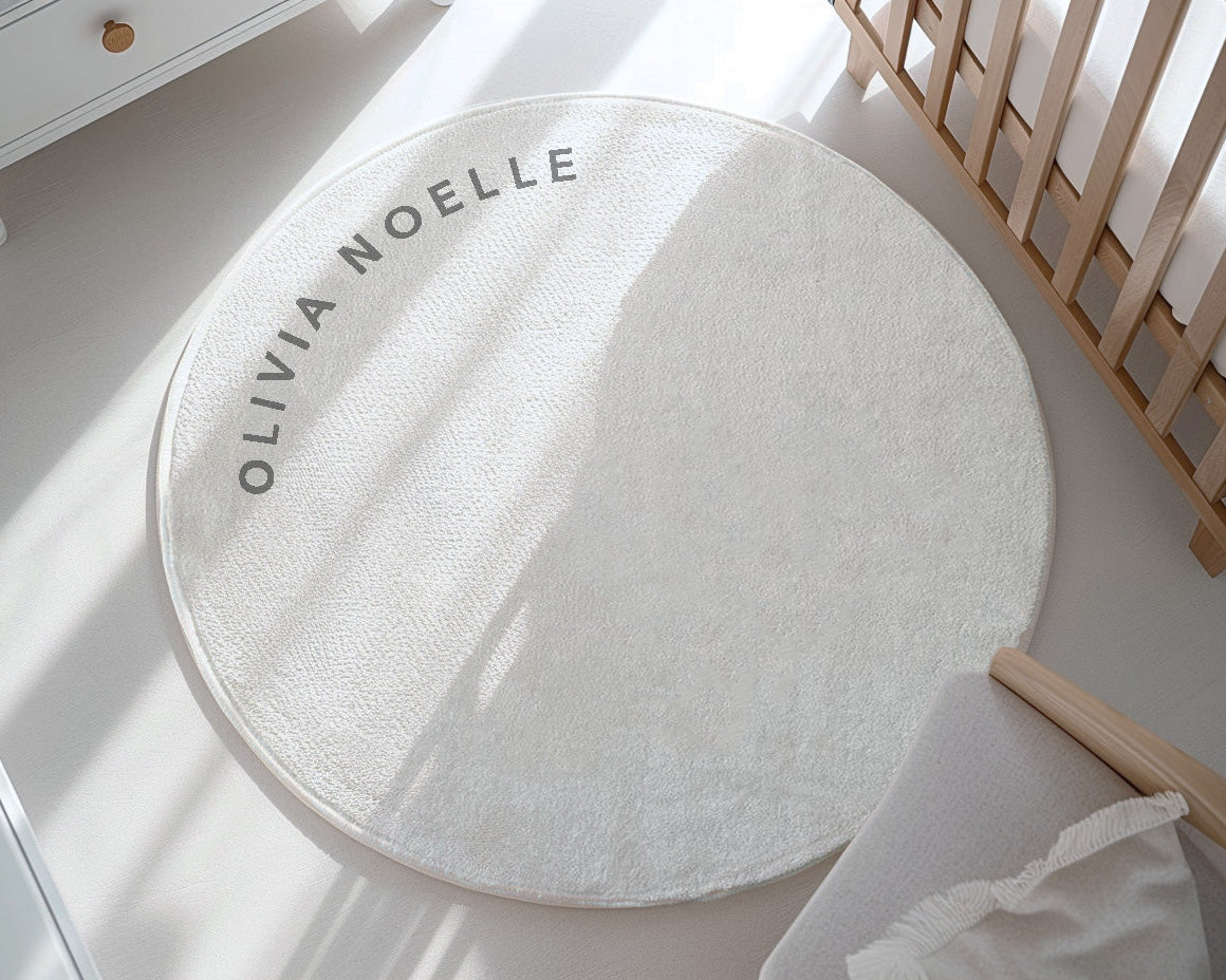 Round white rug with 'Olivia Noelle' branding on a light wooden floor.