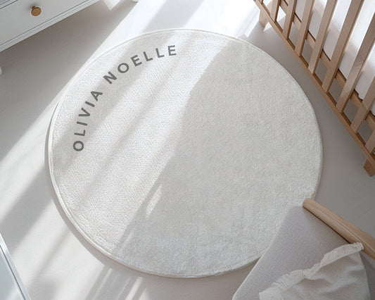 Round white rug with 'Olivia Noelle' branding on a light wooden floor.