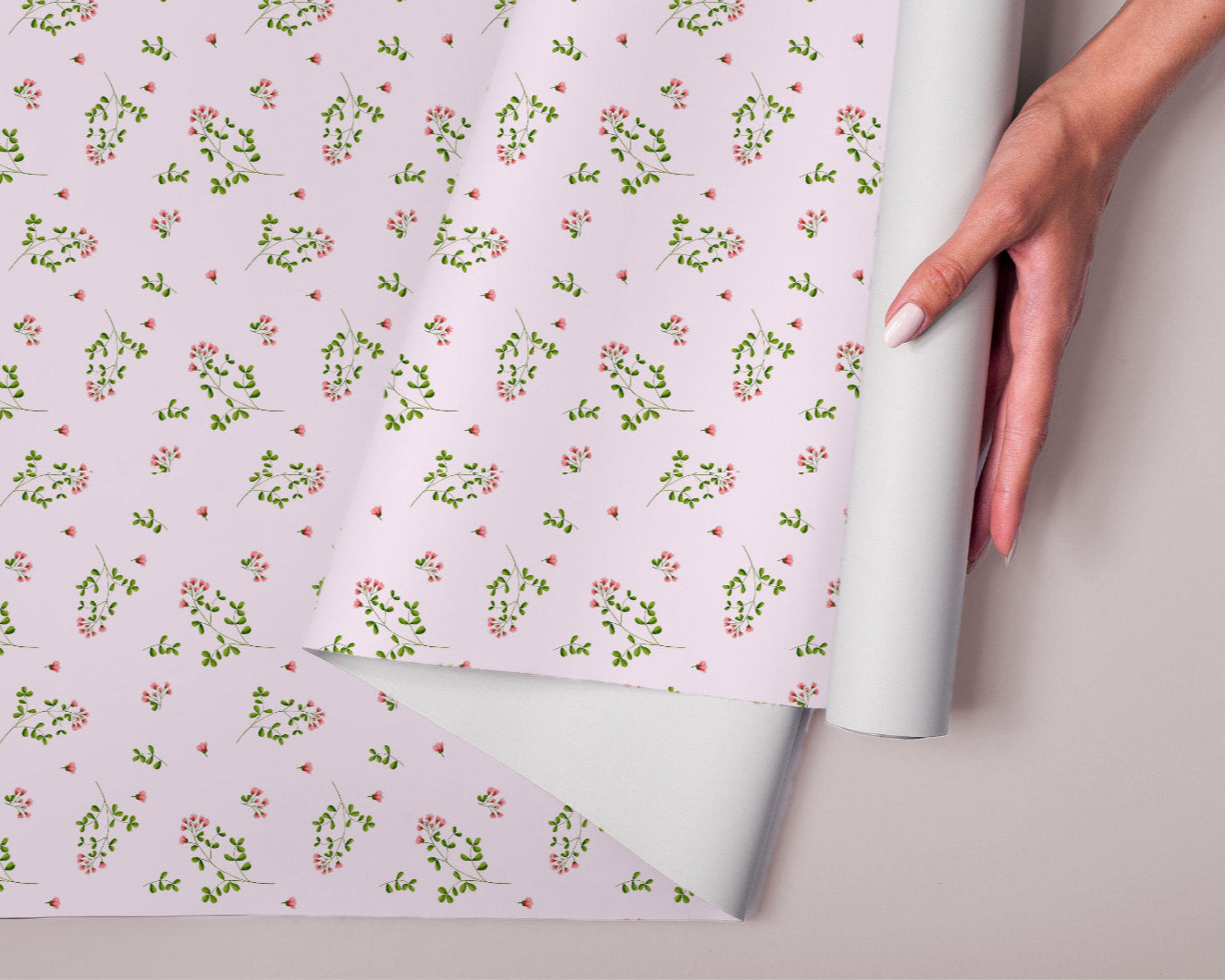 Roll of floral-patterned paper with a hand holding it, on a light background