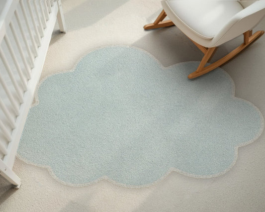Cloud-shaped light blue rug on a neutral floor with a crib and rocking chair.