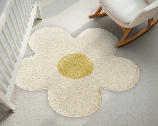Flower-shaped rug with a yellow center on a light gray floor next to a white crib and rocking chair.