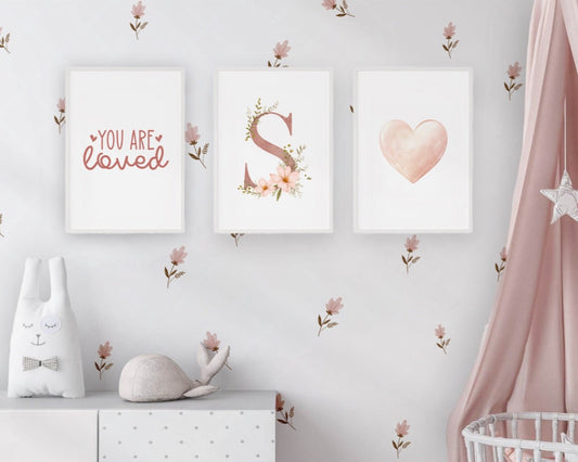 Nursery room with decorative prints, a white cabinet, and a pink curtain.