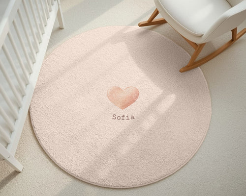 Round pink rug with a heart design and 'Sofia' text in a nursery setting.