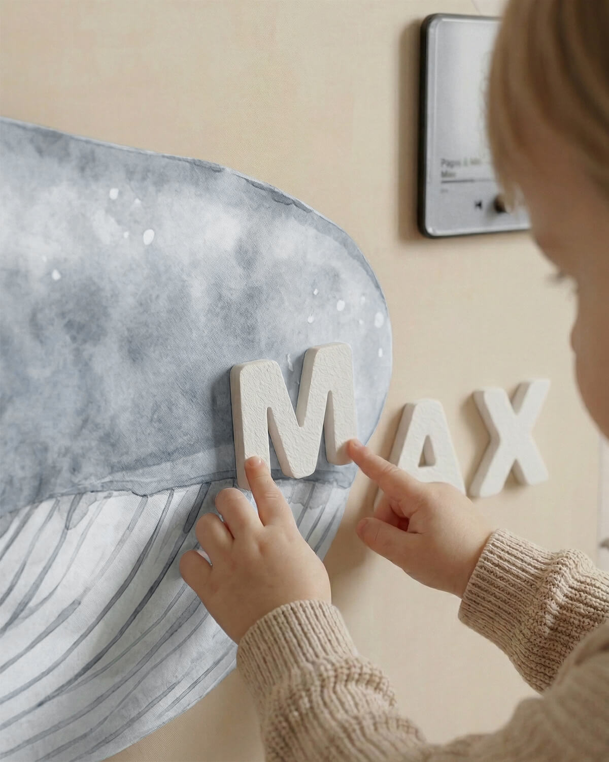 Close-up of a hand placing a premium magnetic letter on a magnetic wall surface.