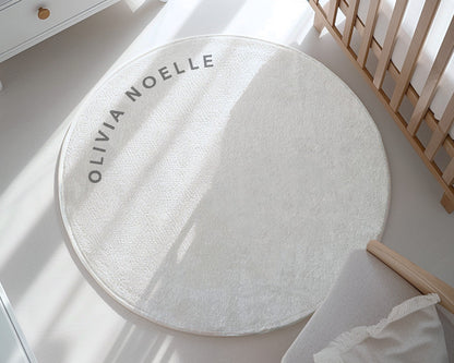 Round white rug with 'Olivia Noelle' branding on a light wooden floor.