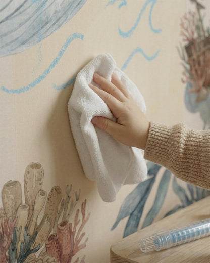 A hand wiping a smudge off a durable, washable magnetic wallpaper for kids' rooms.